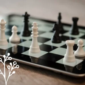 A tablet on the table, with a board on the screen, and chess pieces on top.