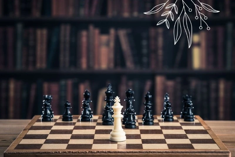 A chessboard with a white king in the center. In the background, a bookshelf with old books.