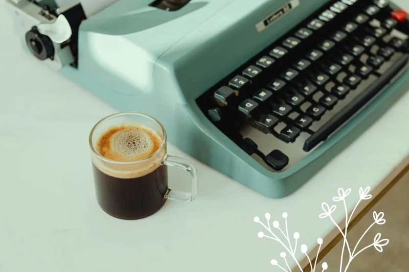 Máquina de datilografar antiga e xícara de café.
