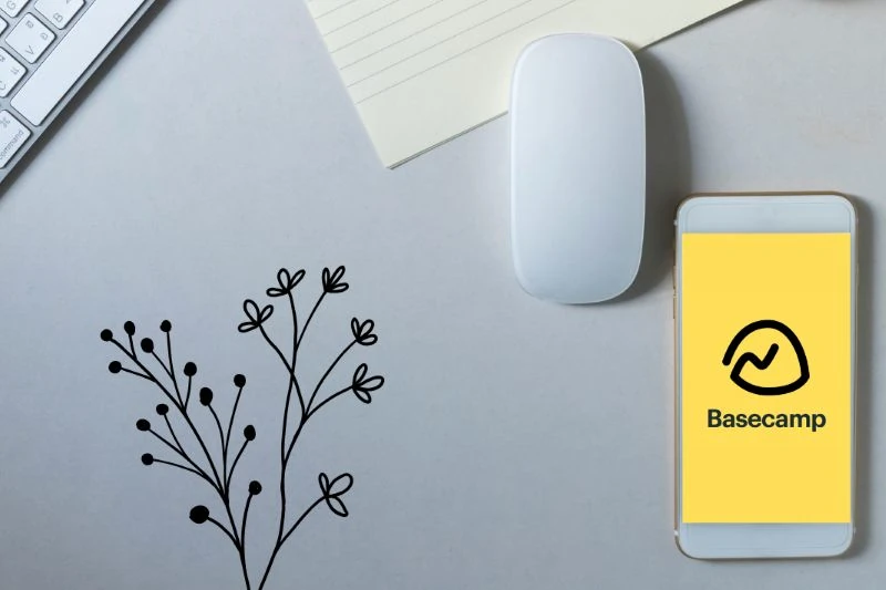 Logo do Basecamp na tela de um celular sobre uma mesa de trabalho.